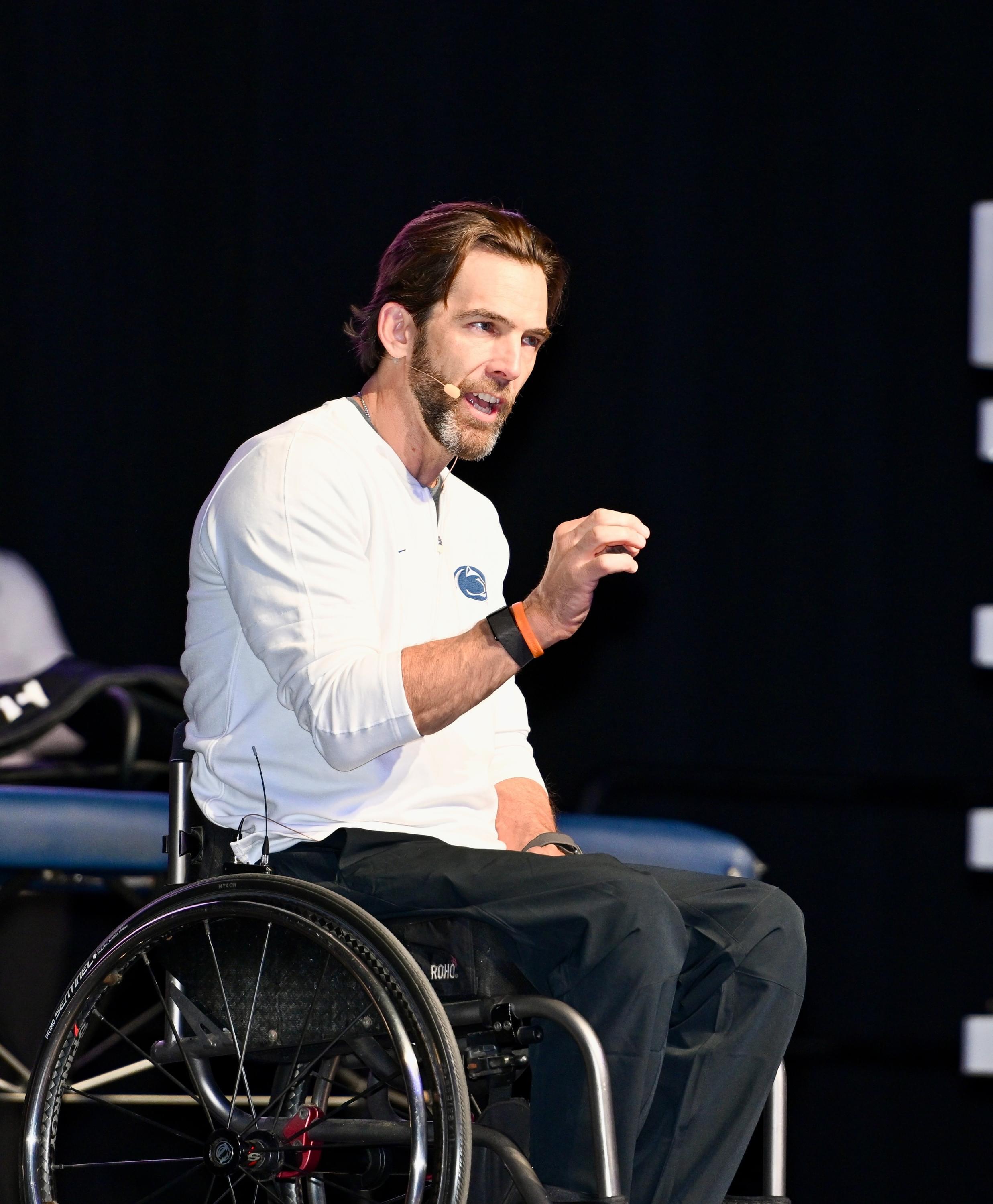 Tom Morris speaking on stage from his wheelchair